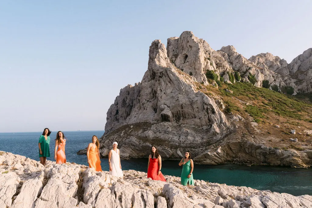 Groupe d'amies alignées sur les rochers des calanques au coucher du soleil pour un EVJF à Marseille