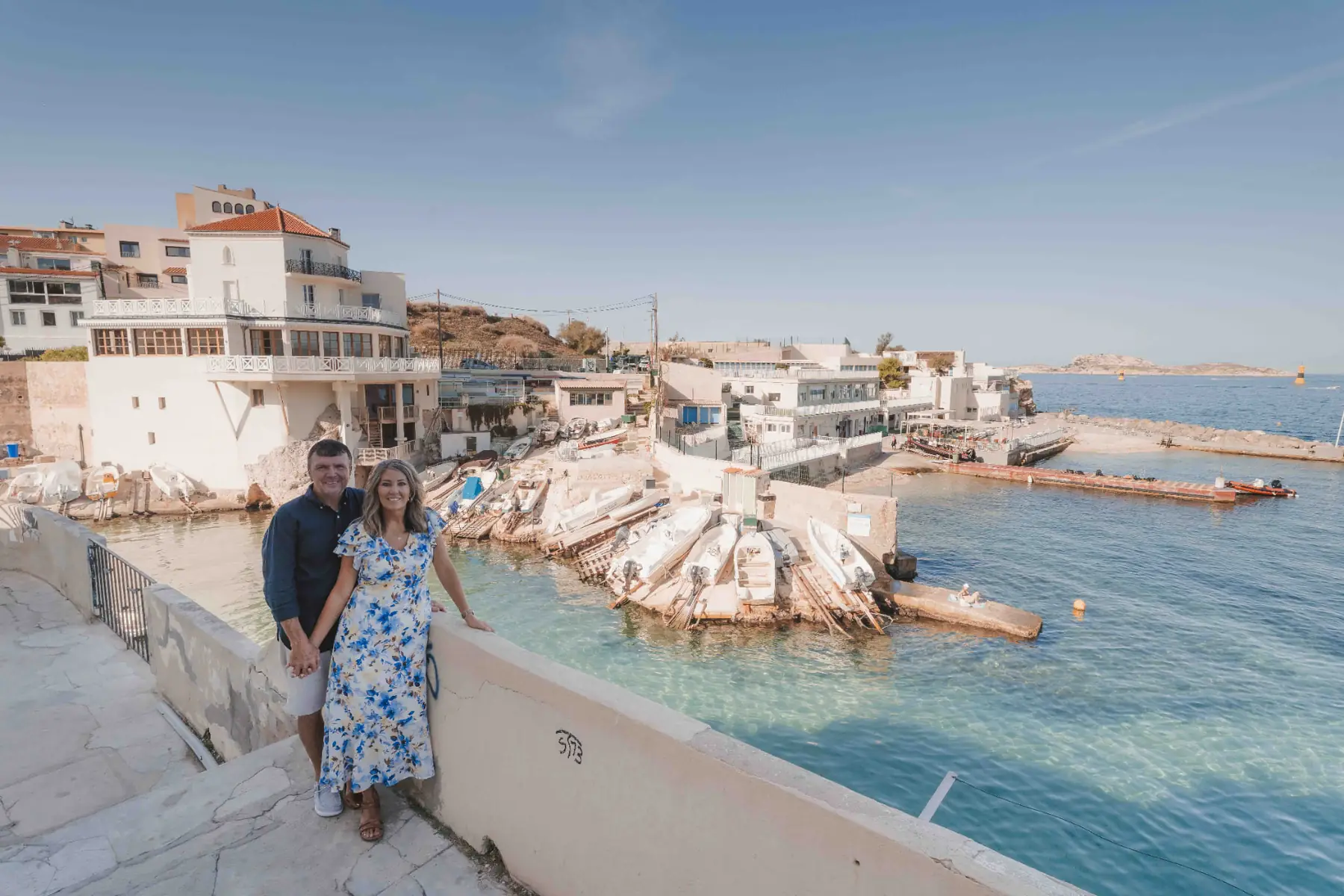 Couple posing above the turquoise cove and moored boats of Malmousque during a photo session in Marseille