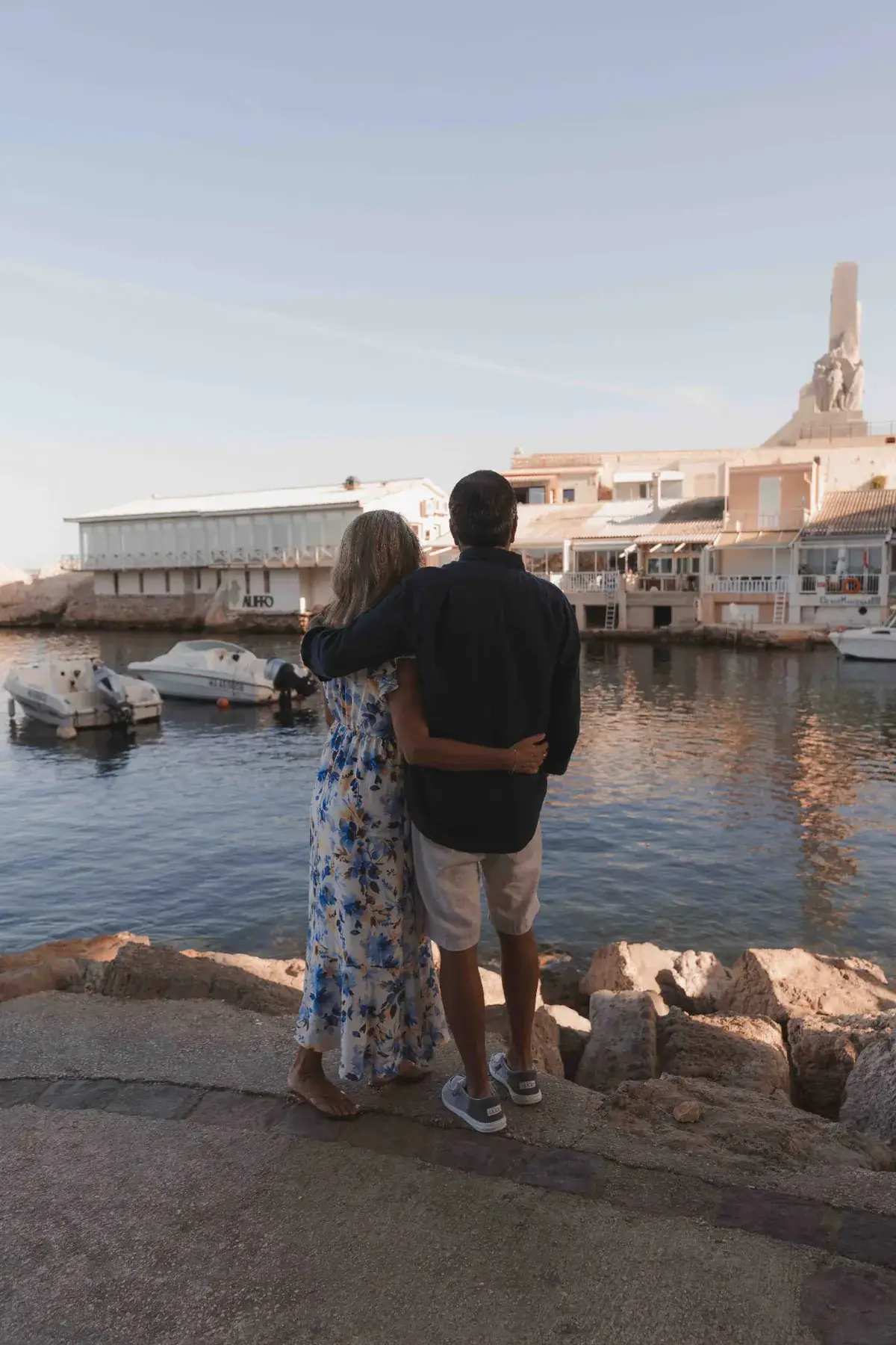 Couple standing arm in arm watching the water at Vallon des Auffes harbour during a Marseille photo walk